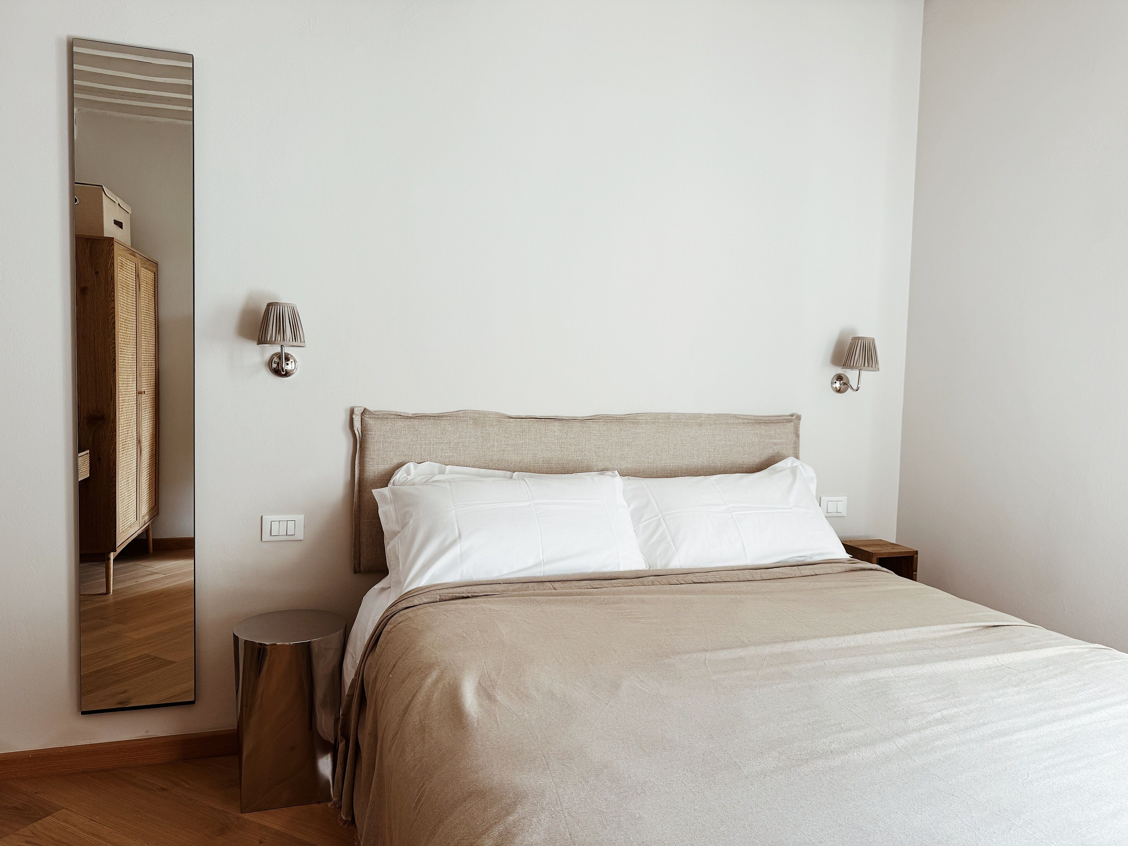 Un dormitorio con cama, mesita de noche, lámpara, espejo y armario.