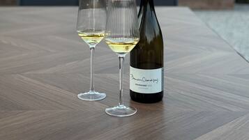 Een fles Domaine Chandon wijn en twee glazen op een houten tafel, met een open haard op de achtergrond.