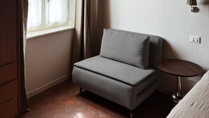 A room with a houndstooth sofa, a framed picture on the wall, a window with curtains, and a lamp. - Villa Sofia (Querceta)