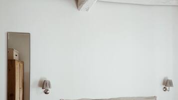 Une chambre à coucher avec un lit, un miroir et deux lampes fixées au mur.