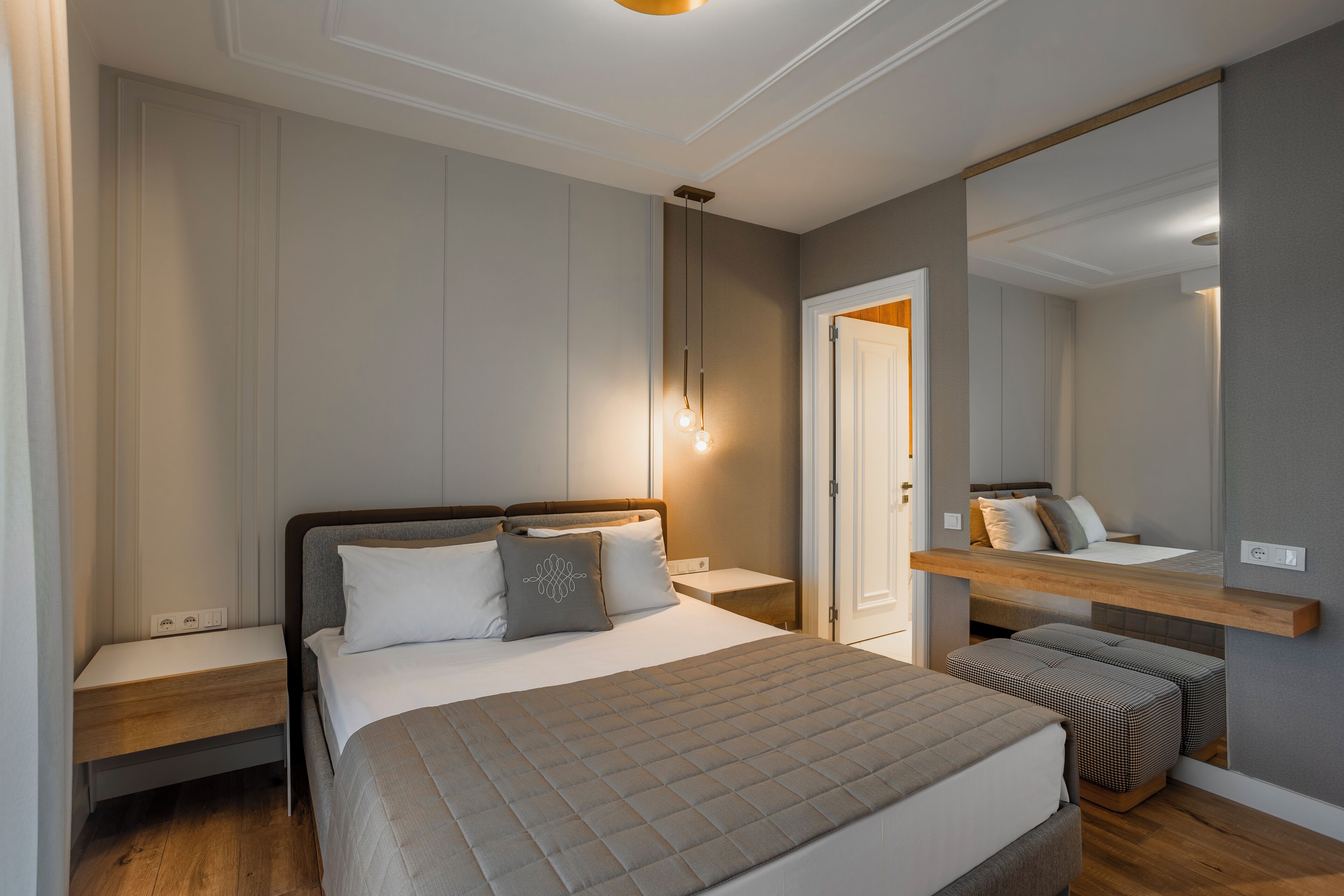 Ein ordentlich eingerichtetes Schlafzimmer mit einem Bett, Nachttischen, einem Spiegel und einem Holzregal.