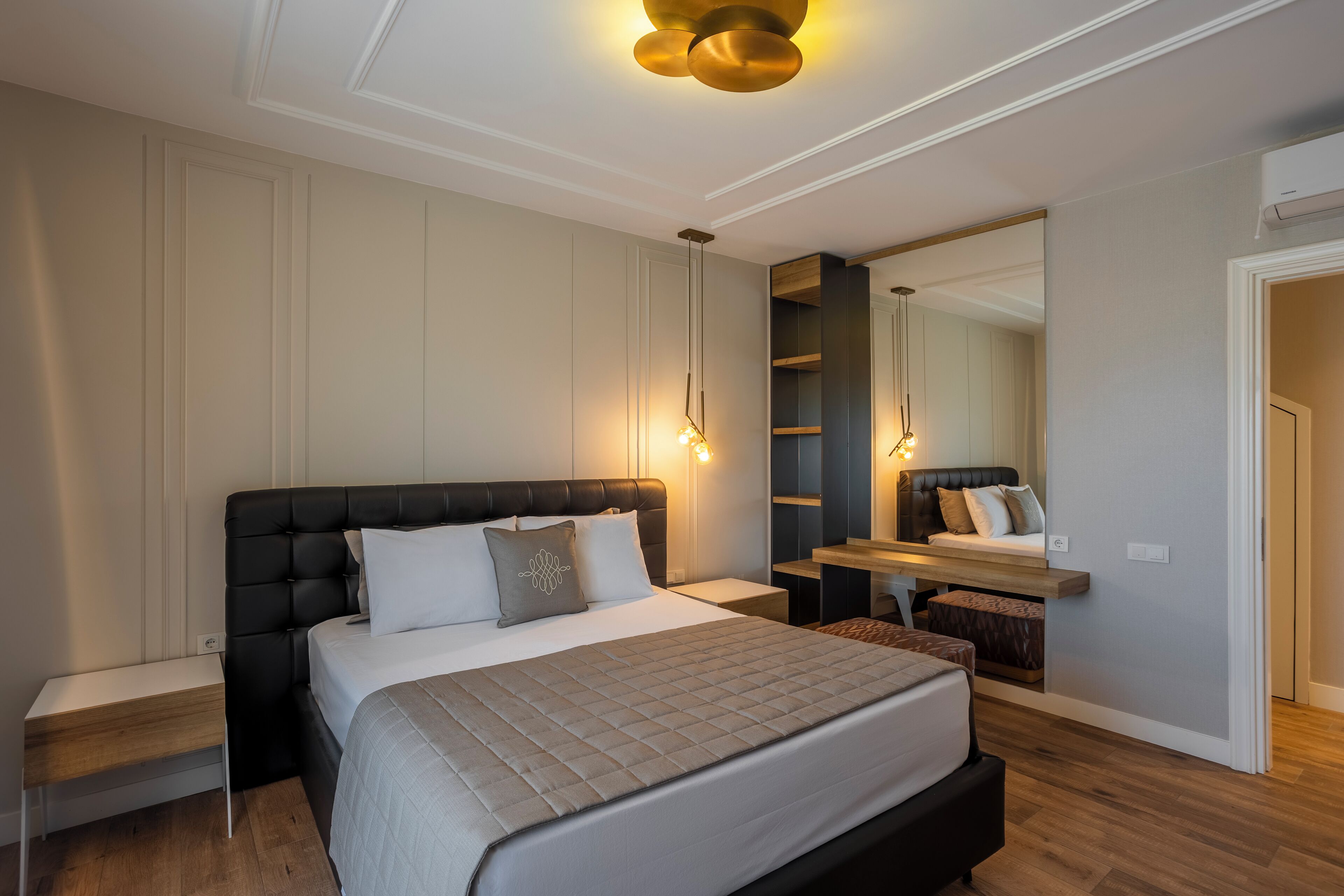 Ein modernes Schlafzimmer mit einem großen Bett, Nachttischen, einem Spiegel und einer integrierten Sitzbank.