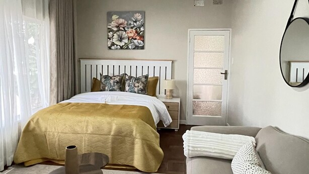 A hotel room with a bed, a sofa, a small table, a mirror, and a door. - The Comfy Private Place - 2296 (Harare)