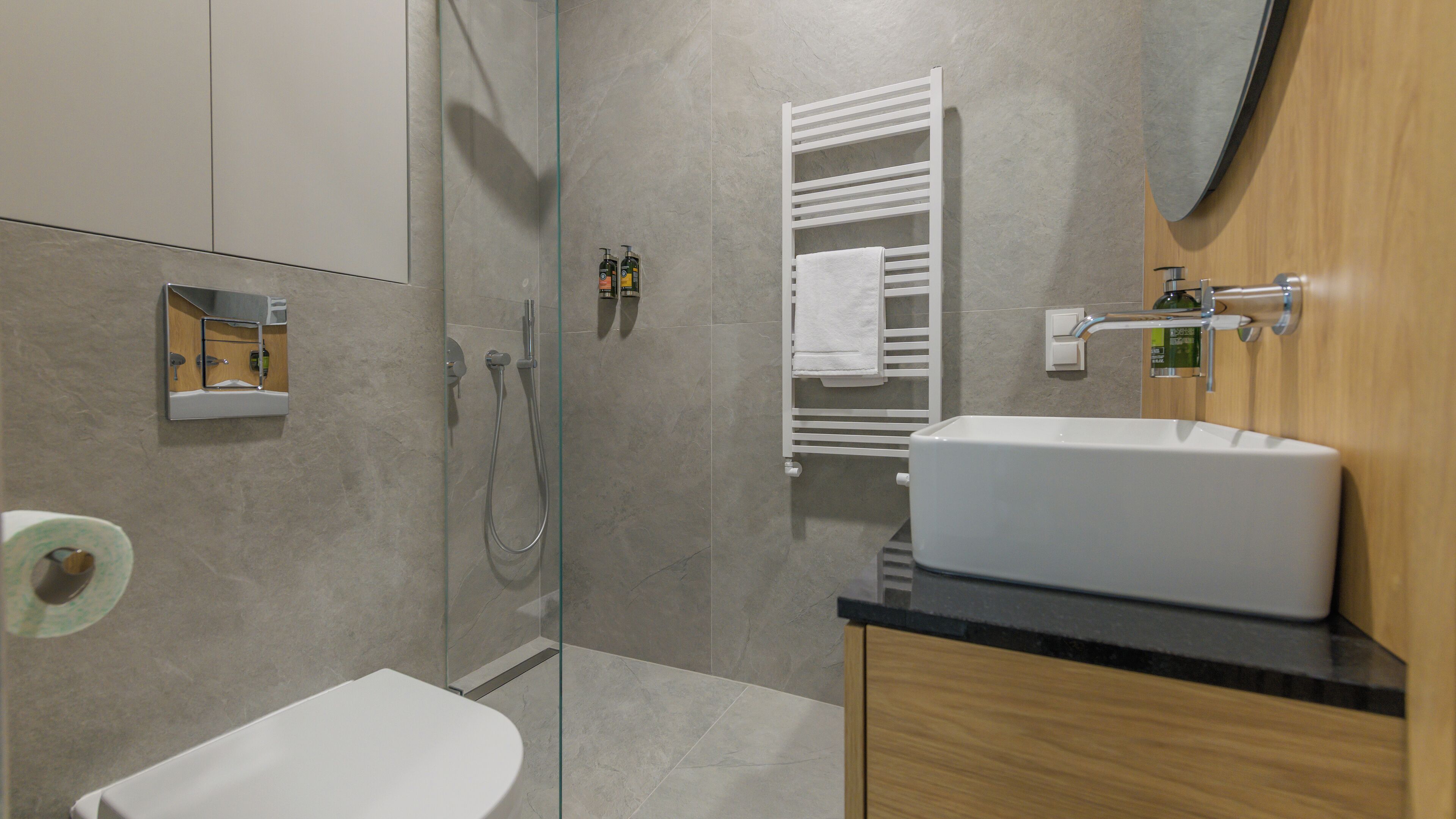 A modern bathroom with a glass-enclosed shower, a white sink, and a wooden vanity.