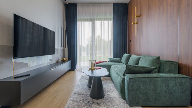 Una sala de estar moderna con un televisor de pantalla plana, un sofá gris, una mesa de centro y un armario de madera.