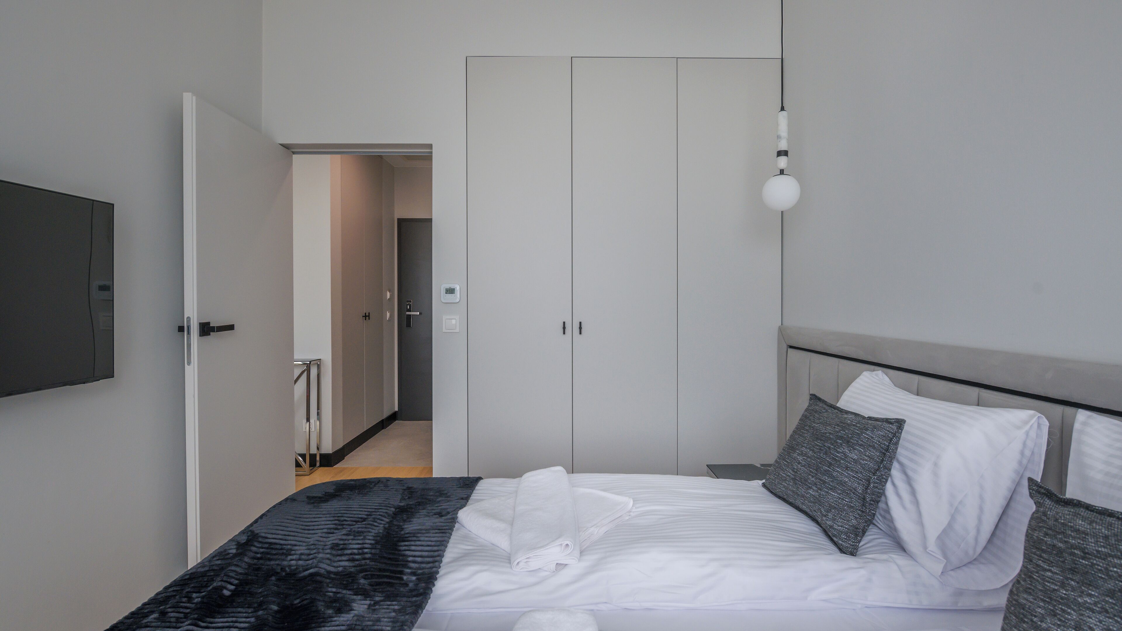 A bedroom with a bed, pillows, a TV, and a wardrobe.