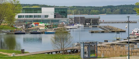 Un port de plaisance avec des bateaux amarrés, un bâtiment moderne et une zone herbeuse avec un distributeur automatique.