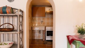 A kitchen with a wooden cabinet, a sink, and a stove. - Casa Abba by Wonderful Italy (Golfo Aranci)