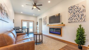 A modern living room with a leather sofa, a fireplace, a television, and artwork on the walls.