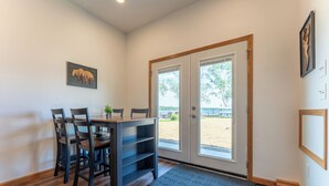A dining area with a table and chairs, a bench, a door leading outside, and a framed picture on the wall.