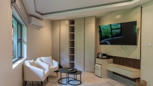 A modern room with a sofa, a small table, a TV, and built-in storage.