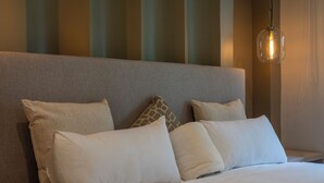 A neatly made bed with white linens and a grey headboard.