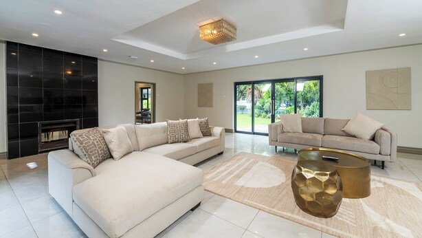 A spacious living room with a large L-shaped beige sofa, a round gold coffee table, and a fireplace.