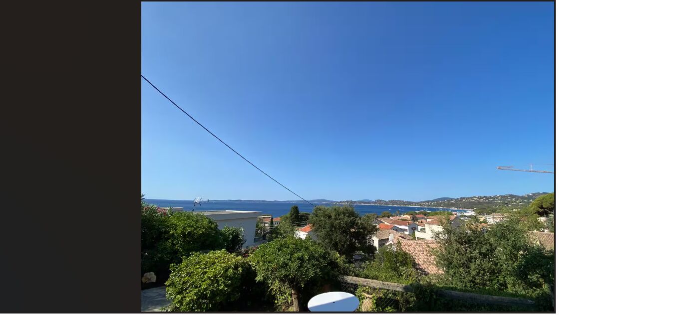 A coastal view with a clear sky, a body of water, and buildings in the distance.