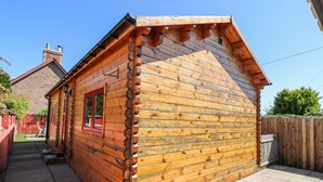 Una cabaña de madera con techo inclinado, una ventana pequeña y una puerta.