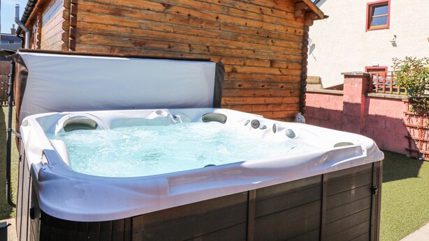 Una cabaña de madera con un jacuzzi al frente.