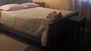 A bedroom with a bed, a nightstand, a lamp, and a chair. - Cozy detached house in the historic center of Umbertide indoor garden (Umbertide)