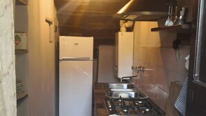 A narrow kitchen with a refrigerator, stove, and tiled backsplash. - Cozy detached house in the historic center of Umbertide indoor garden (Umbertide)