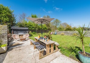 Enjoy al fresco dining and cooking on the patio, surrounded by lush greenery and a grill.