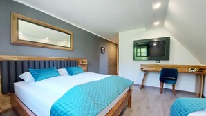 Une chambre d’hôtel moderne, dotée d’un grand lit, d’un bureau et d’une télévision.