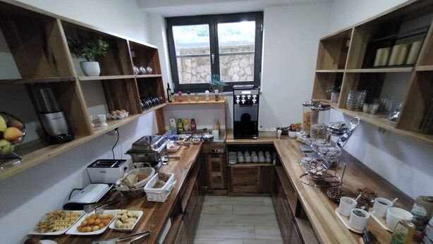 Un buffet de petit-déjeuner proposant une variété d’aliments et de boissons, des étagères en bois et une machine à café.
