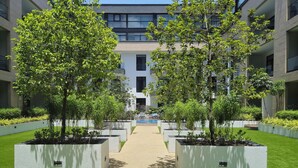 A modern building with a central pathway flanked by greenery and planters. - Ebs properties  (Accra)