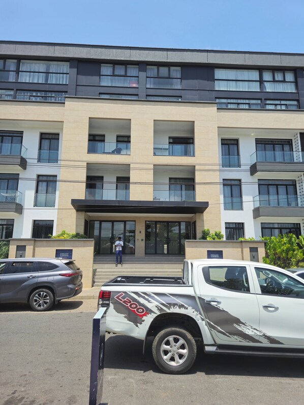 A multi-story building with a flat facade, large windows, and a central entrance with steps. - Ebs properties (Accra)