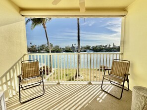 Enjoy breathtaking views of the lake from this balcony, featuring two comfortable chairs and a small table.