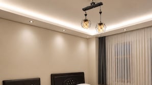 Moderni hotellihuone, jossa on kaksi sänkyä, suuri ikkuna verhoilla, kattovalaisin ja patteri.