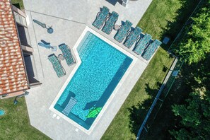 A rectangular swimming pool with a green inflatable flamingo, surrounded by lounge chairs and umbrellas. - Pool and Fun Villa Stella Klarici (Svetvincenat)