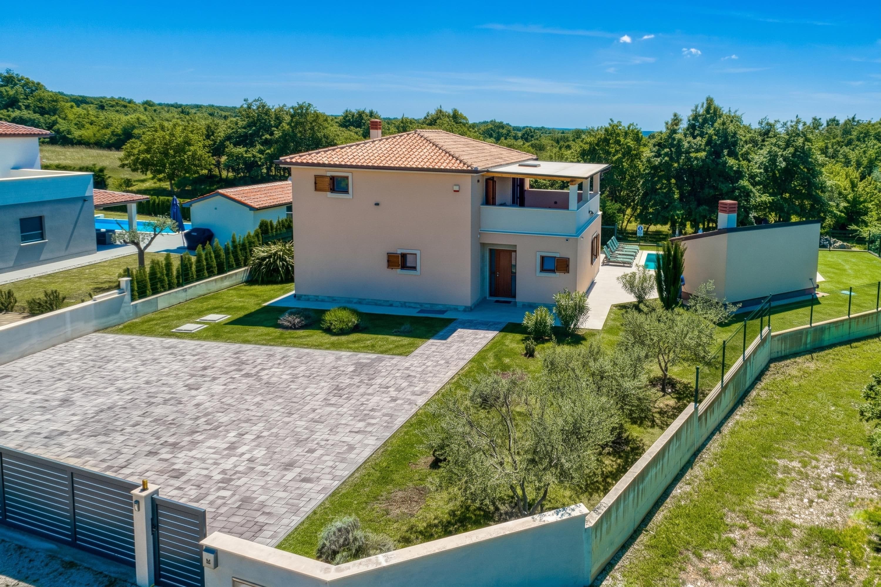 Une maison à deux étages avec une piscine, entourée d’une cour clôturée et de verdure.