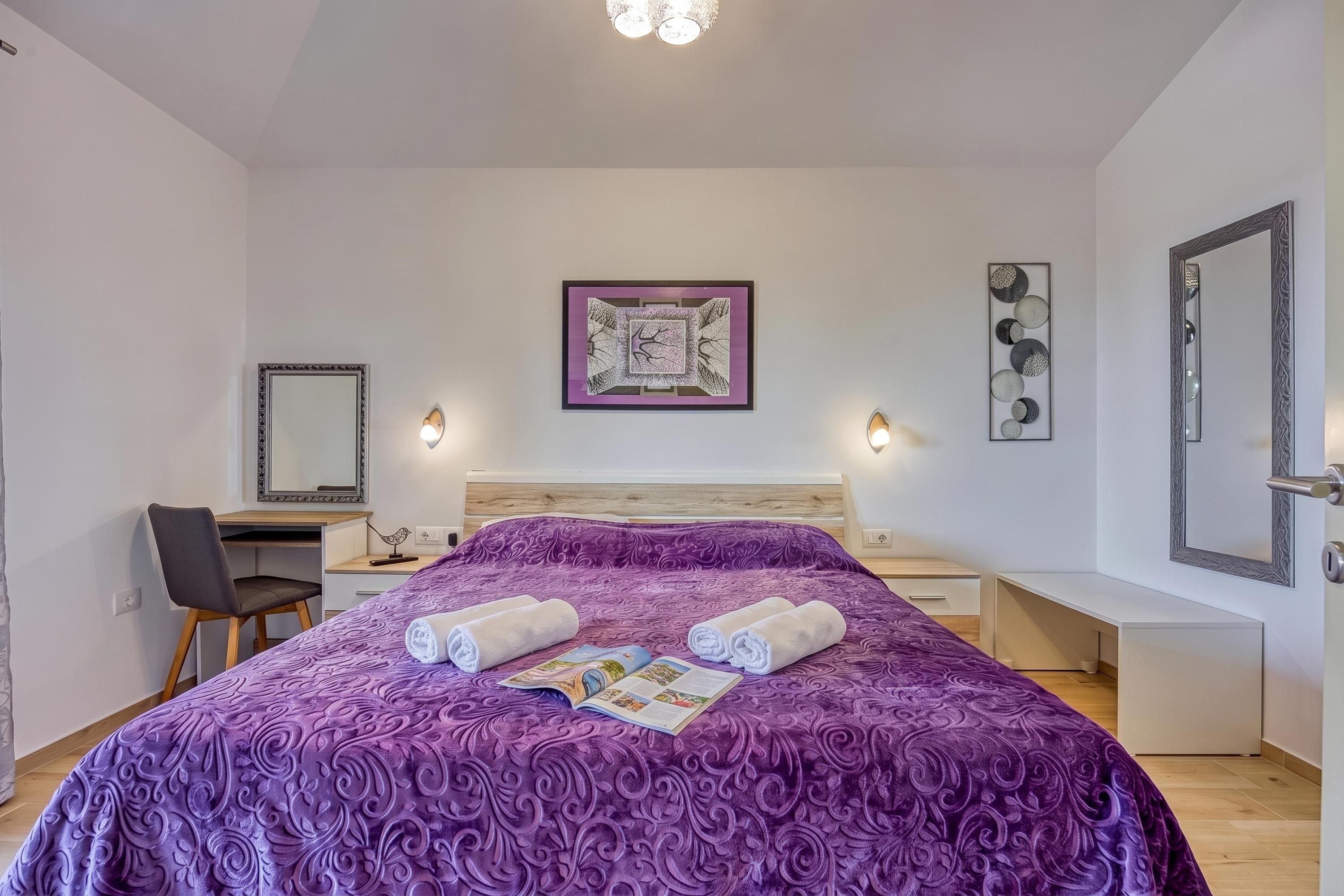 Une chambre d’hôtel avec un grand lit, un bureau, une chaise, une table de chevet et un miroir.