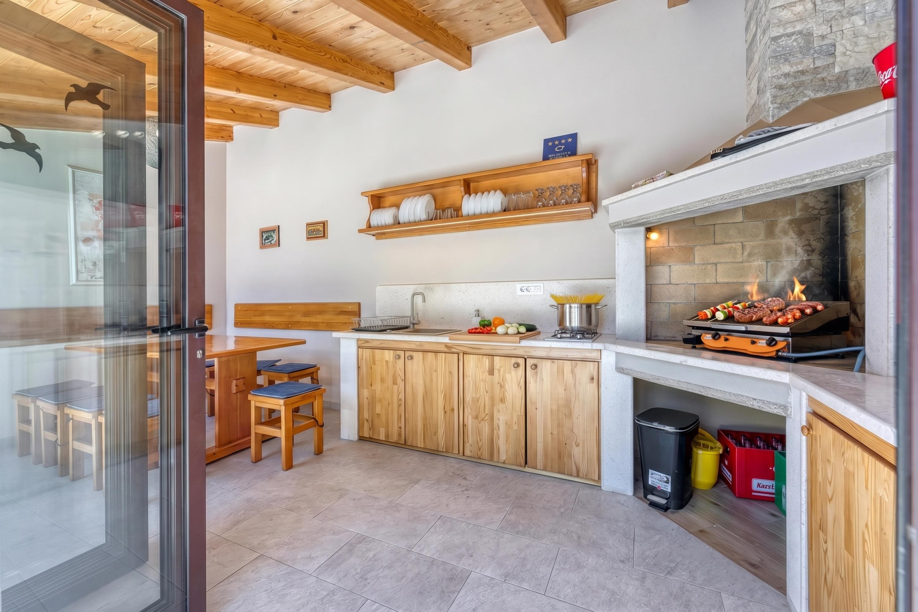 Una cocina moderna con armarios de madera, una parrilla integrada y acceso por puerta de vidrio.