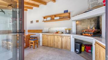Una cocina moderna con armarios de madera, una parrilla integrada y acceso por puerta de vidrio.