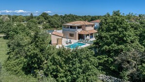 Ein zweistöckiges Haus mit Swimmingpool, umgeben von Bäumen.
