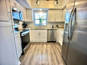 Een moderne keuken met witte kasten, roestvrijstalen apparatuur en een houten vloer.