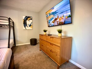 A bedroom with a bunk bed, a wooden dresser, a flat-screen TV, and a painting on the wall. - Heated Pool & Basketball, Sleeps 12 | Tropical Dream Villa, Valrico / Brandon (Valrico)