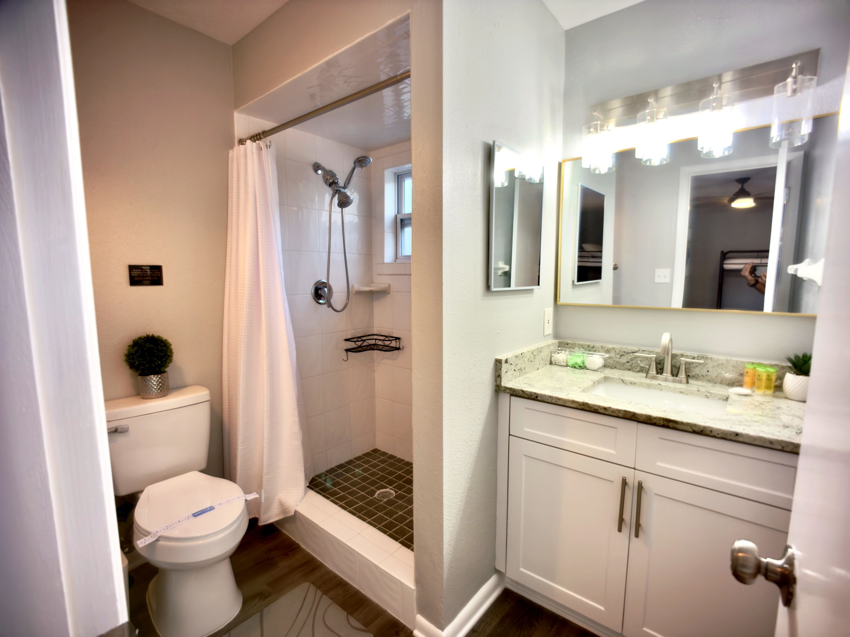 A bathroom with a toilet, shower, sink, and vanity.