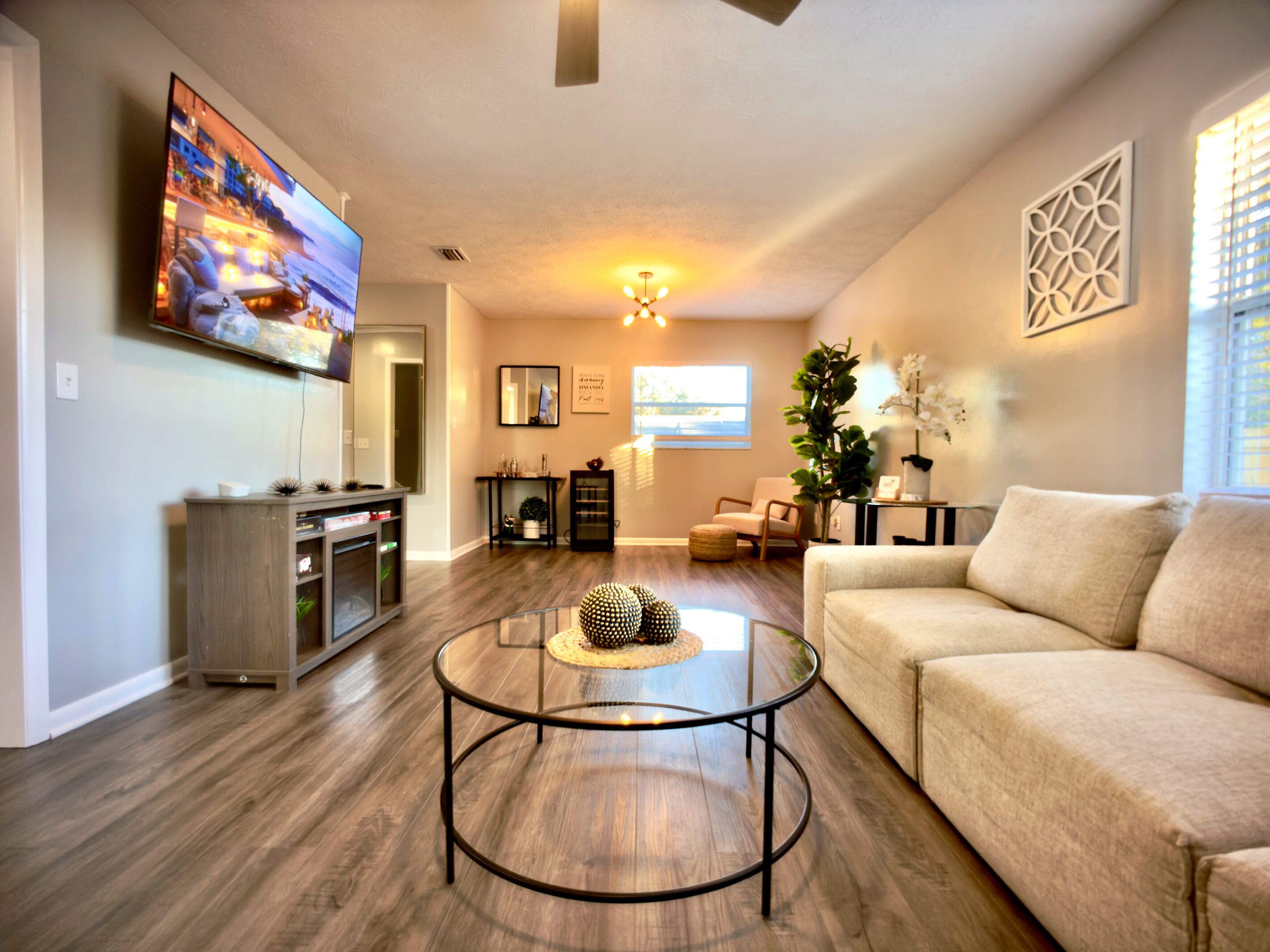 Una sala de estar con una televisión de pantalla plana, una mesa redonda de centro, un sofá y una planta decorativa.