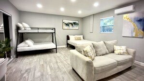 Une chambre moderne avec un lit superposé, un canapé et une fenêtre avec des stores.