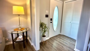 Un couloir avec une lampe, une plante en pot et une porte dotée d’une fenêtre en verre dépoli.