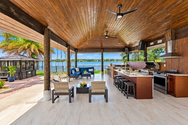 A covered outdoor area with a bar and seating, overlooking a body of water.
