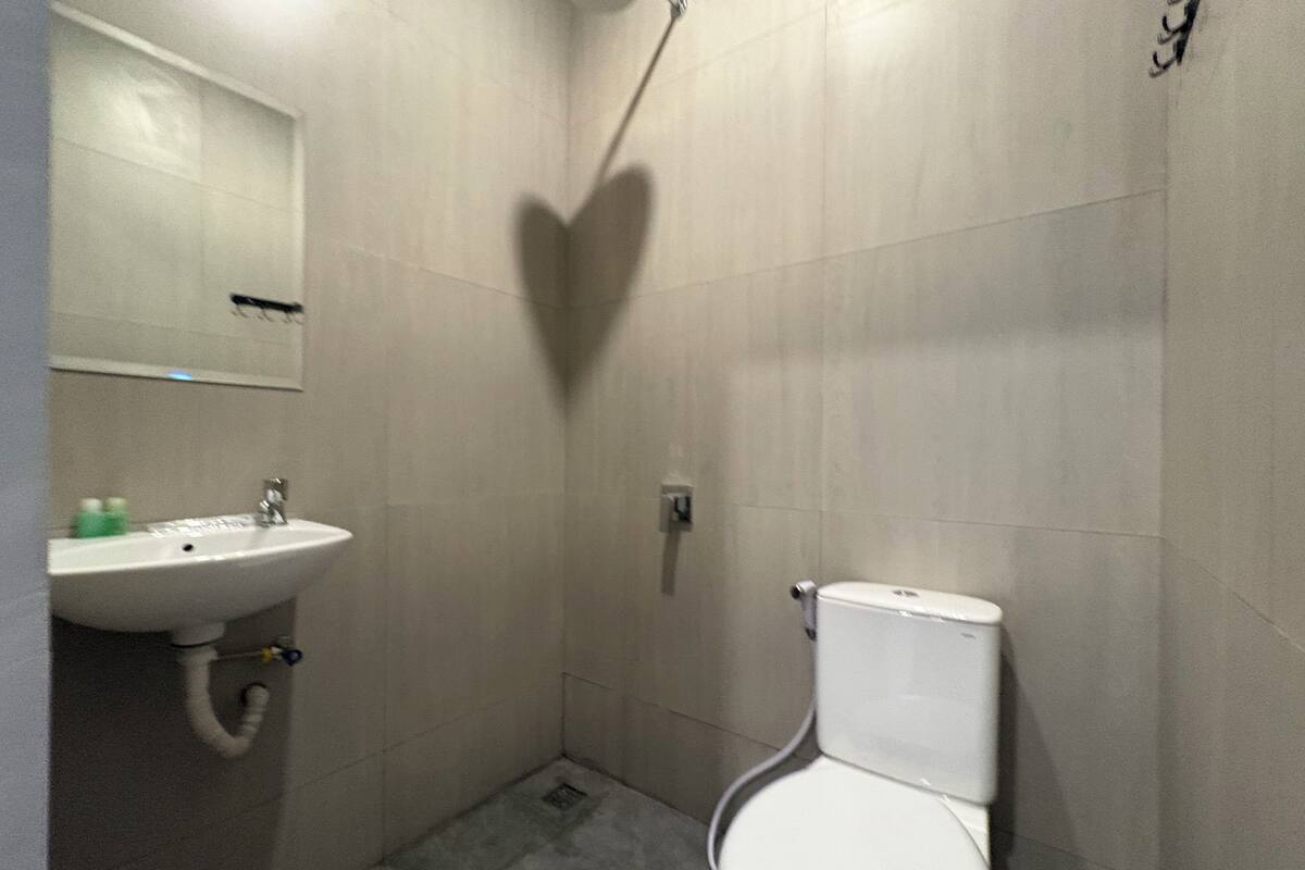 Une petite salle de bain avec un lavabo, des toilettes et une douche, le tout de couleur blanche.