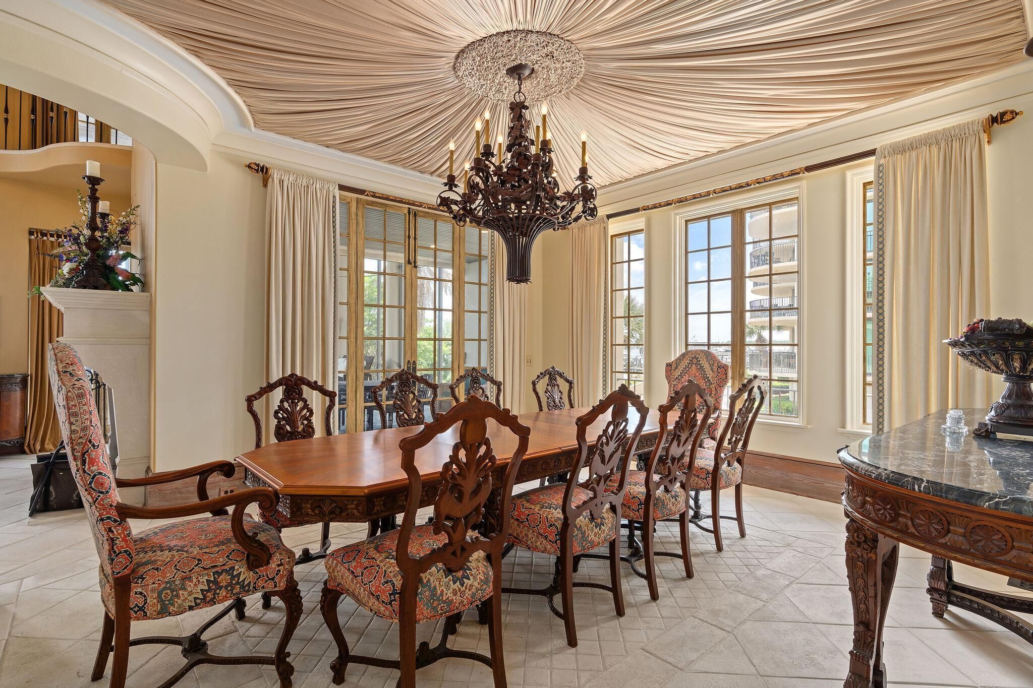 Un comedor formal con una gran mesa de madera, sillas ornamentadas y una araña.