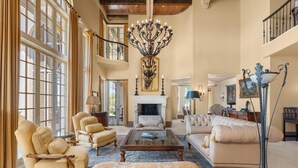 A spacious living room with a fireplace, large windows, and elegant furniture. - Villa Grande (Orange Beach)