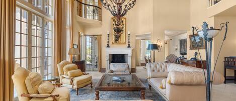 A spacious living room with a fireplace, large windows, and elegant furniture.