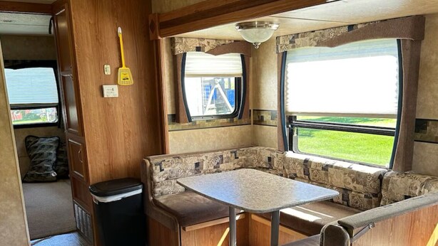 Een compact RV-interieur met een kitchenette, een eethoek en een raam met uitzicht op de natuur.