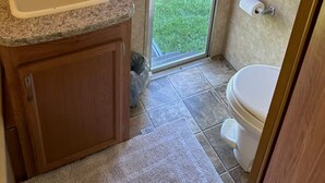 Een kleine badkamer met wastafel, toilet en een klein raam.