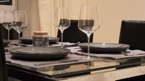 Een eettafel gedekt met borden, glazen en een potje sausjes.