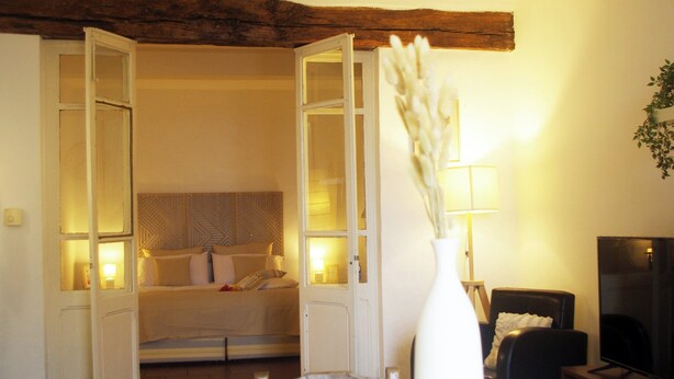 Een hotelkamer met een bed, een eettafel, een televisie en een vaas met gedroogde bloemen.